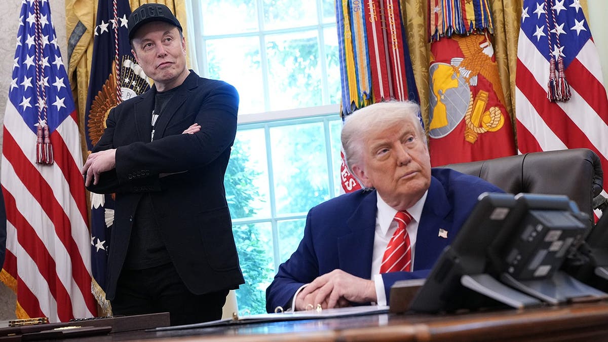 Elon Musk and Donald Trump listen to reporters in the Oval Office.