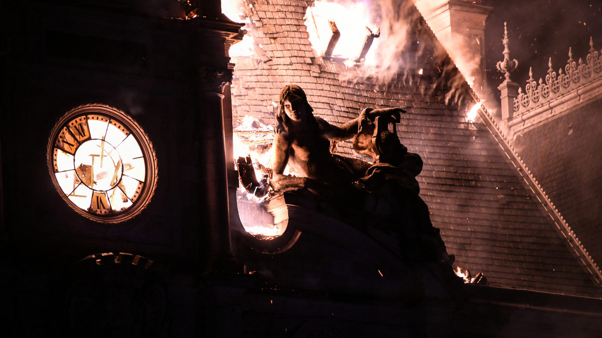 This photograph shows a fire burning and destroying the city hall after a group of individuals forced entry into the building during ongoing protest action against the 