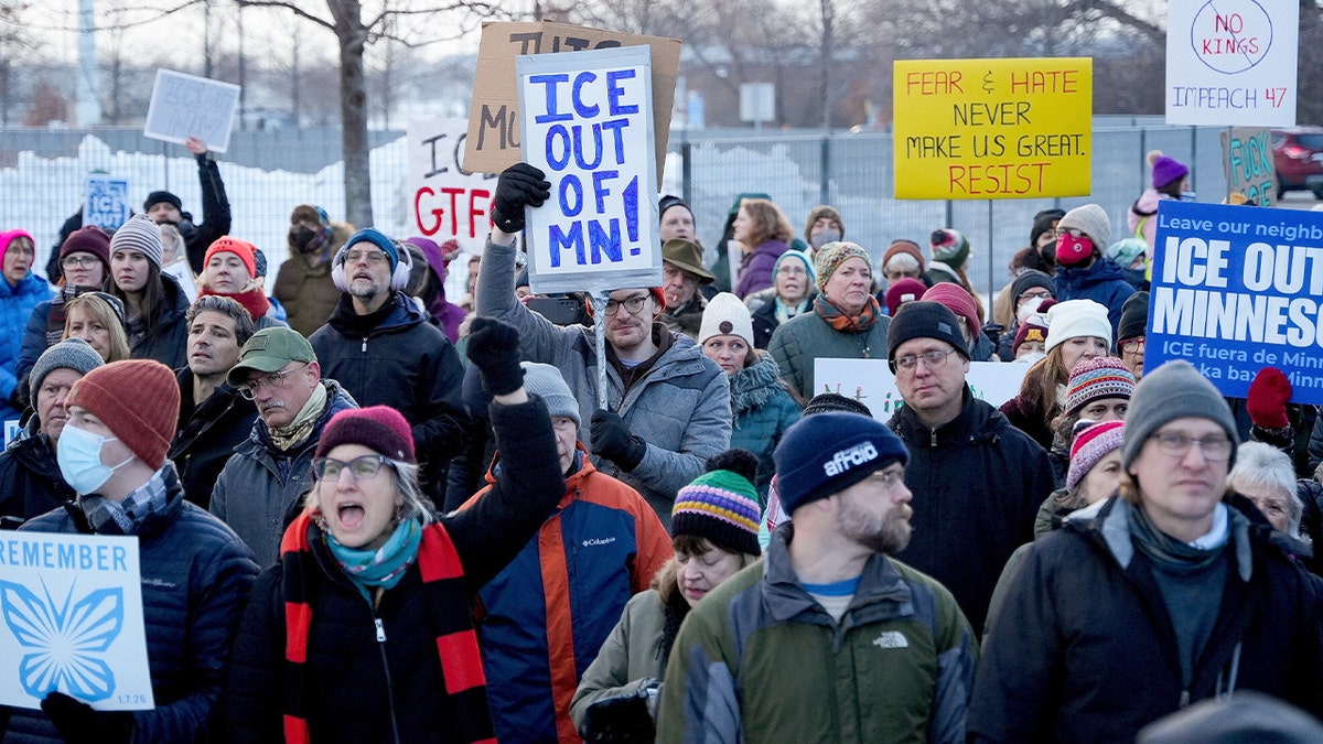 Demonstrators hold signs and gather outside a government building during an immigration enforcement protest.