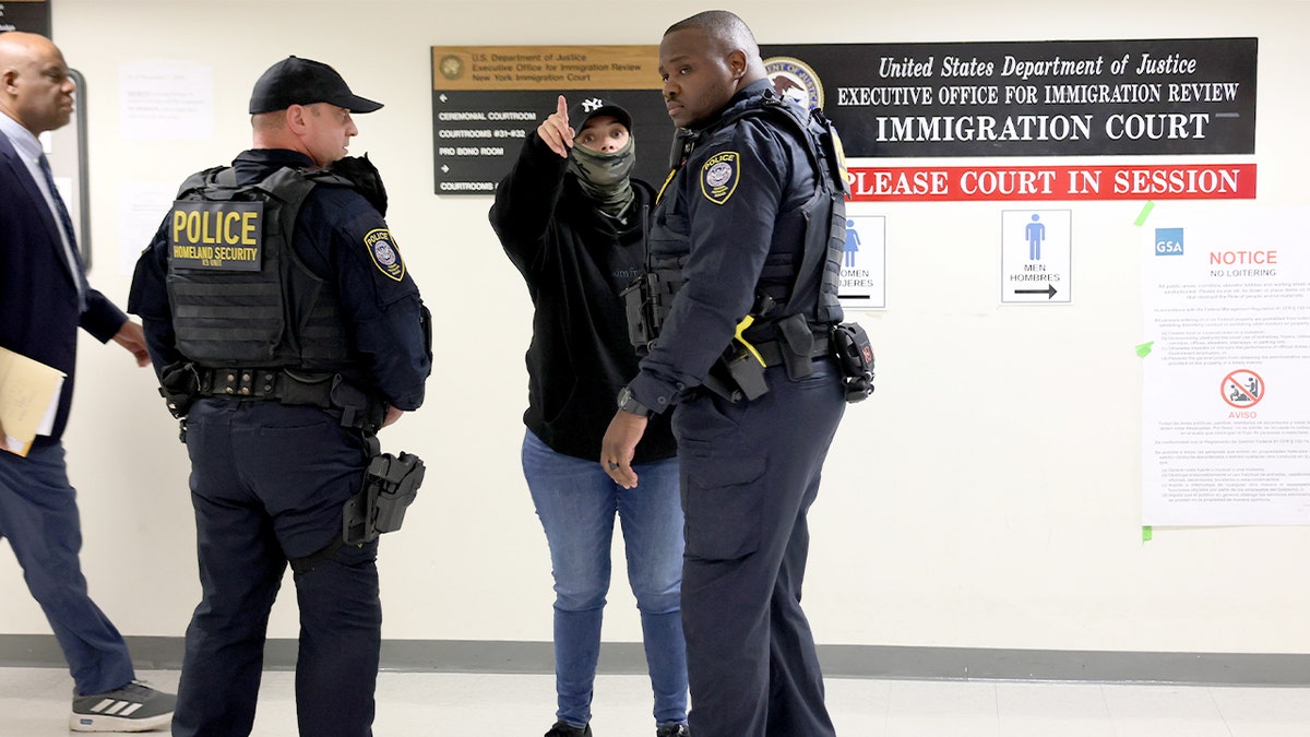 Uniformed officers converse with a plainclothes agent while monitoring a corridor inside a federal courthouse.