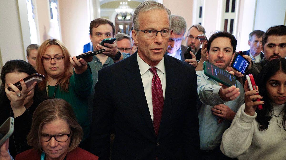 John Thune talks with reporters while walking to his office at the U.S. Capitol.
