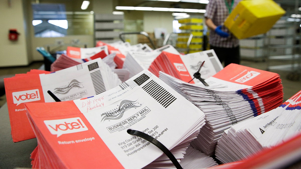 stacks of mail in ballot envelopes