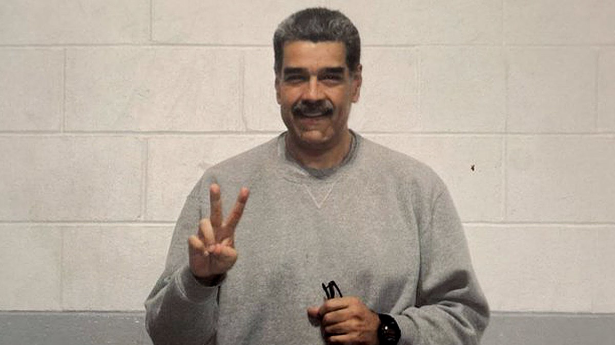 nicolas maduro in gray sweatsuit holding a peace sign and smiling