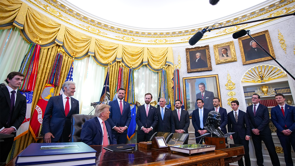 President Donald Trump sits at the Resolute Desk surrounded by JD Vance, Nick Shirley and officials during a fraud task force announcement