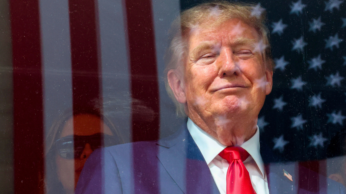 An American flag is reflected off bulletproof glass as U.S. President Donald Trump watches the end of the NTT INDYCAR Series on August 23, 2026 in Washington, DC.