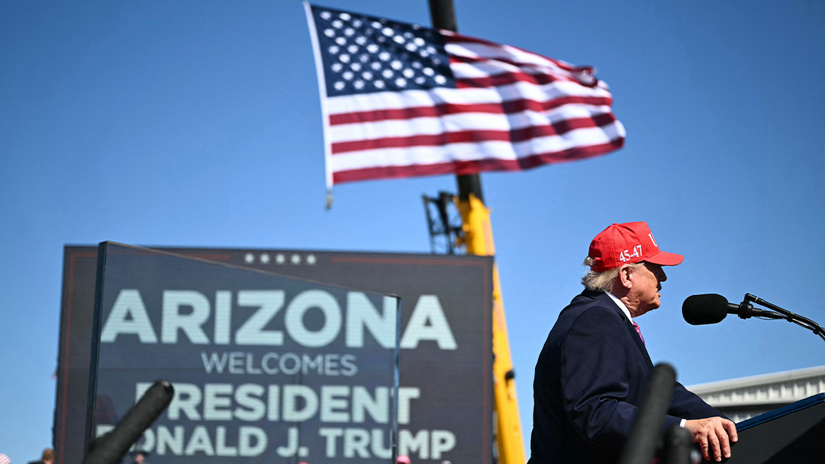 President Donald Trump speaks at a podium beneath an American flag during his Arizona campaign rally
