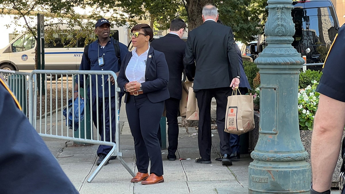 Staff in suits carries brown paper bags to Manhattan court house
