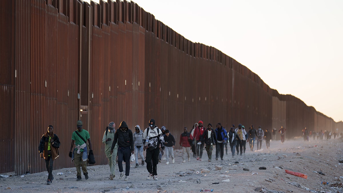 Migrants near the border wall in Arizona