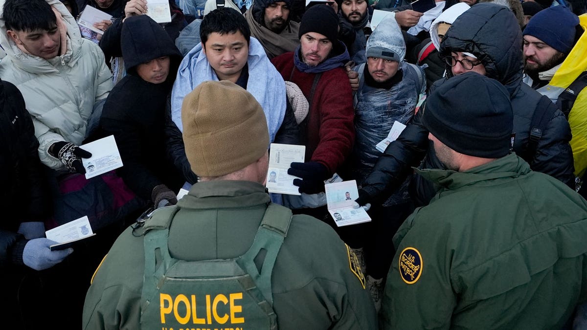Border Patrol agents ask asylum-seeking migrants to line up in a makeshift, mountainous campsite after the group crossed the border with Mexico